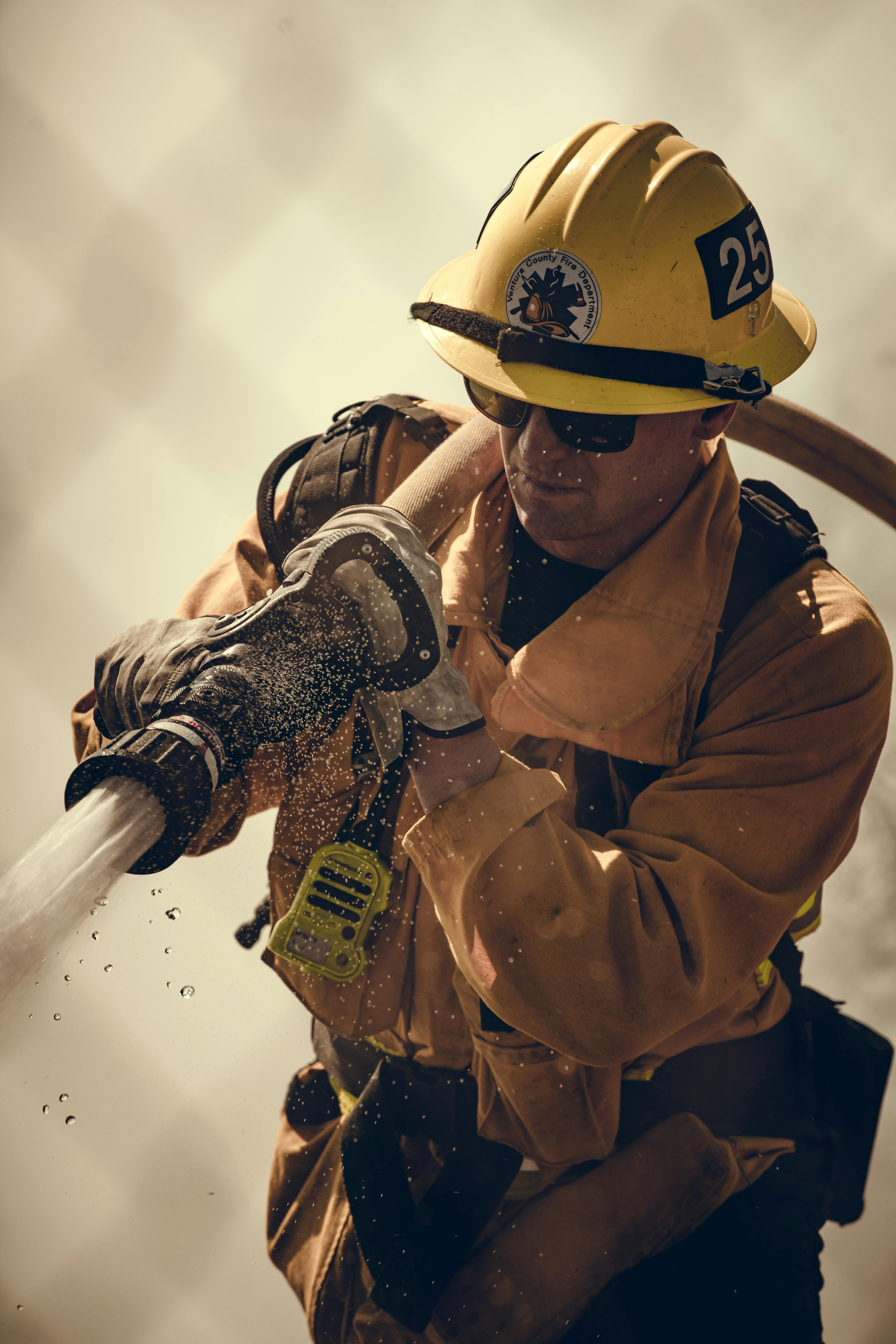 Firefighter equipped with protective gear sprays water during an emergency response.